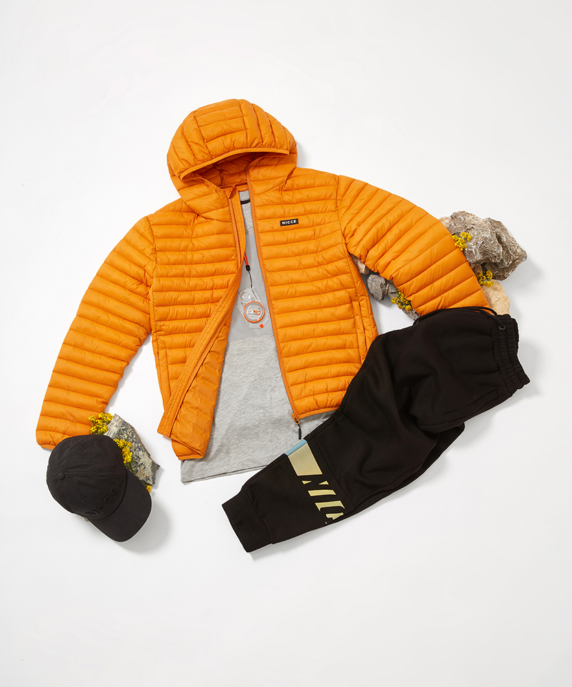 Orange Nicce jacket laid out on floor with black joggers and cap